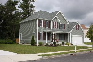 A two-story home with green vinyl siding.