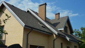 A brick home with gray shingle roofing.