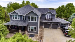 Aerial view of a grey home with shingled roofing and a black car in the driveway 