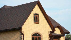 Yellow home with brown shingle roofing 