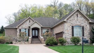 Large house with stone siding and a grey roof