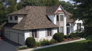 Large house with grey shingle roofing and windows with grey shutters 