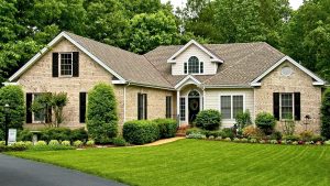 Tan roof on brick home with large green lawn